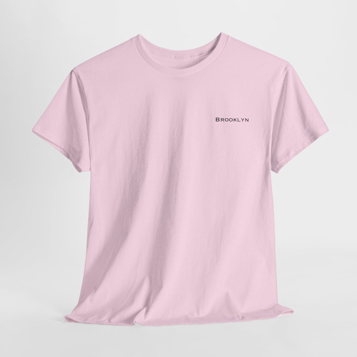 Front view of a pink Brooklyn unisex T-shirt with small black lettering on the left chest.