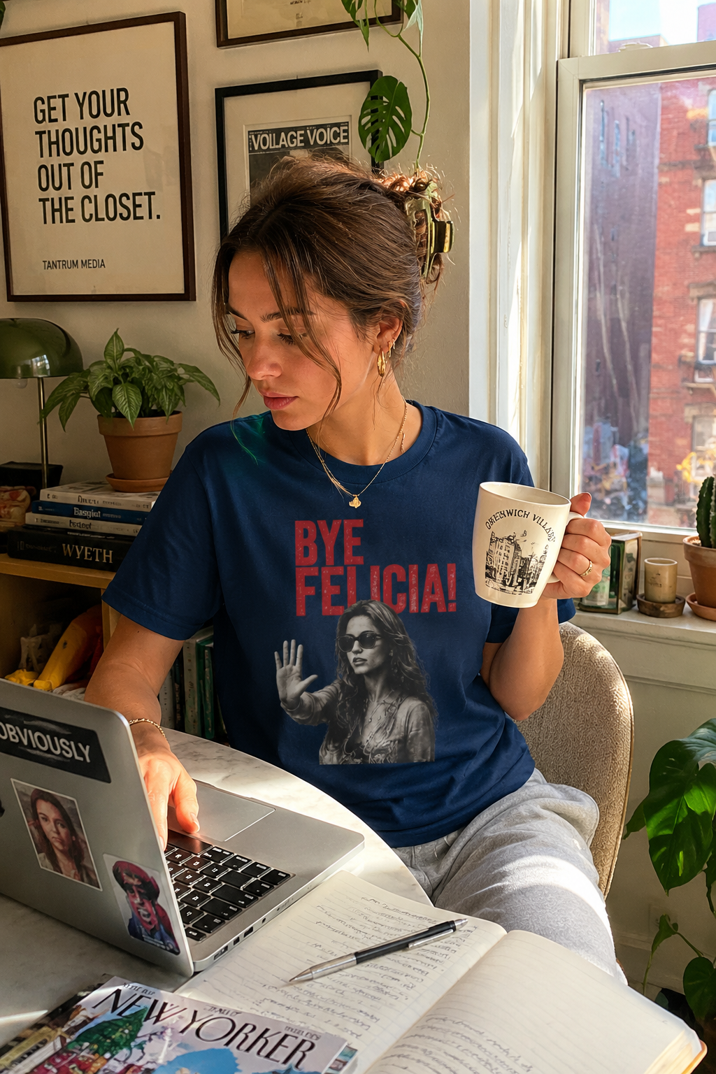 Female millennial wearing Bye Felicia graphic t-shirt writing on laptop in apartment