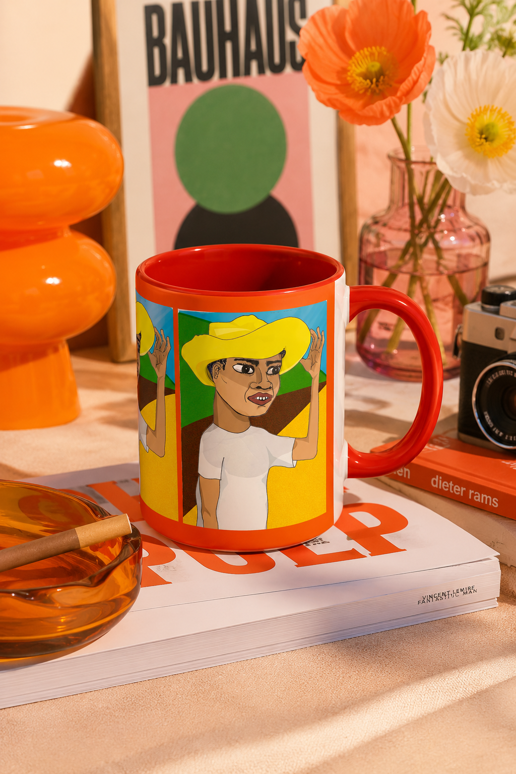 Colorful Cafetero Coffee Mug with red handle and original artwork displayed beside coffee, books, and breakfast items.