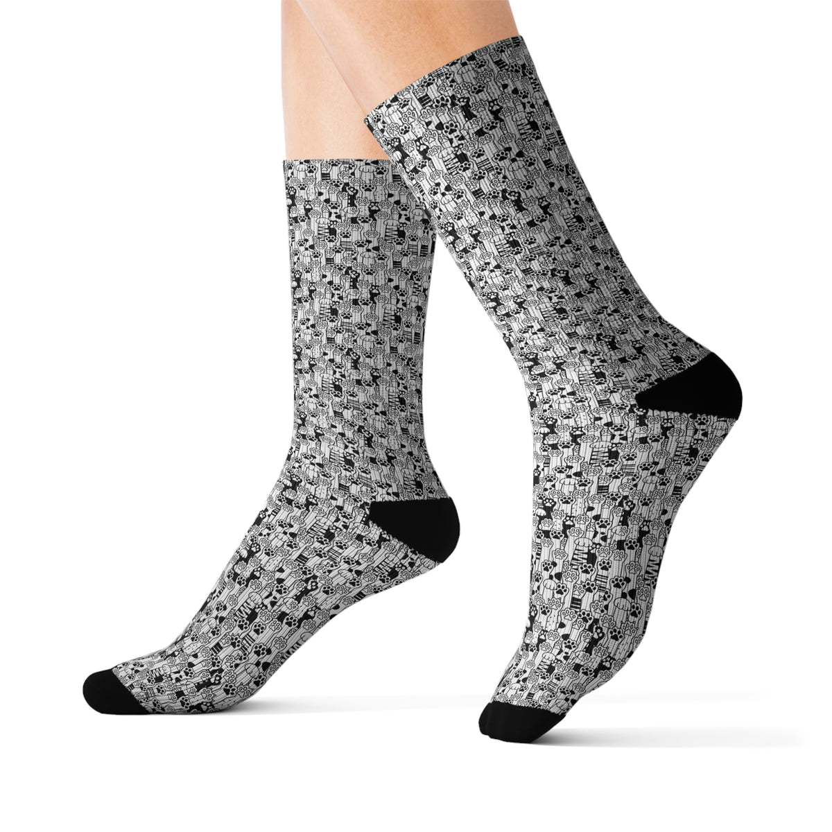 Angled worn view of black and white cat paw print crew socks.