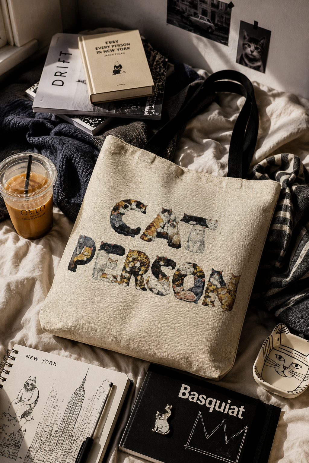 Cat Person woven tote bag styled with art books, a sketchbook, iced coffee and cat-themed college essentials
