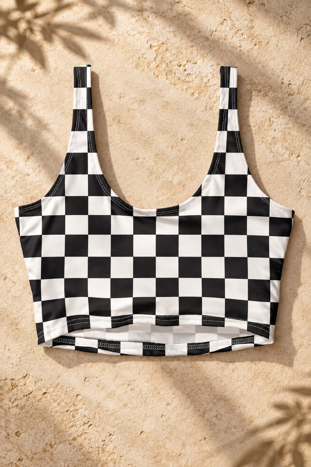 Black and white checkerboard sports bra showing its U-shaped back and wide straps on a gray textured background.