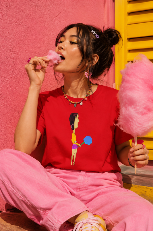 Woman wearing colorful cotton candy graphic T-shirt while eating pink cotton candy in playful editorial summer scene