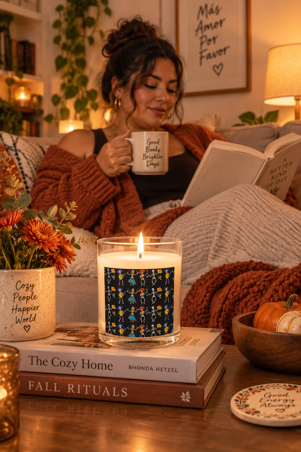 Lit Dancing Skeletons candle in a cozy fall reading nook with a woman relaxing on a sofa