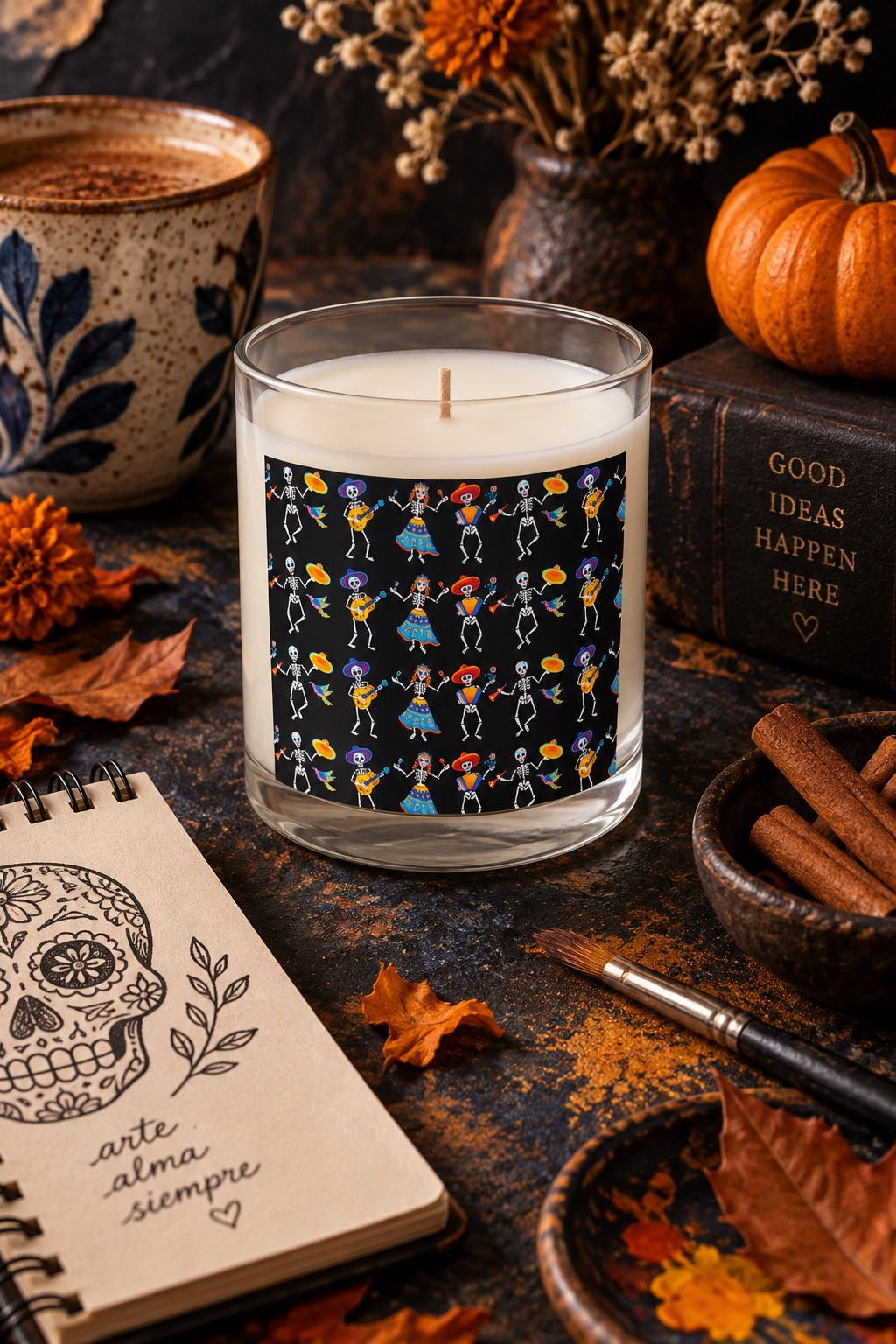 Dancing Skeletons candle styled with cinnamon sticks, pumpkin, dried flowers and sketchbook in a moody fall setting