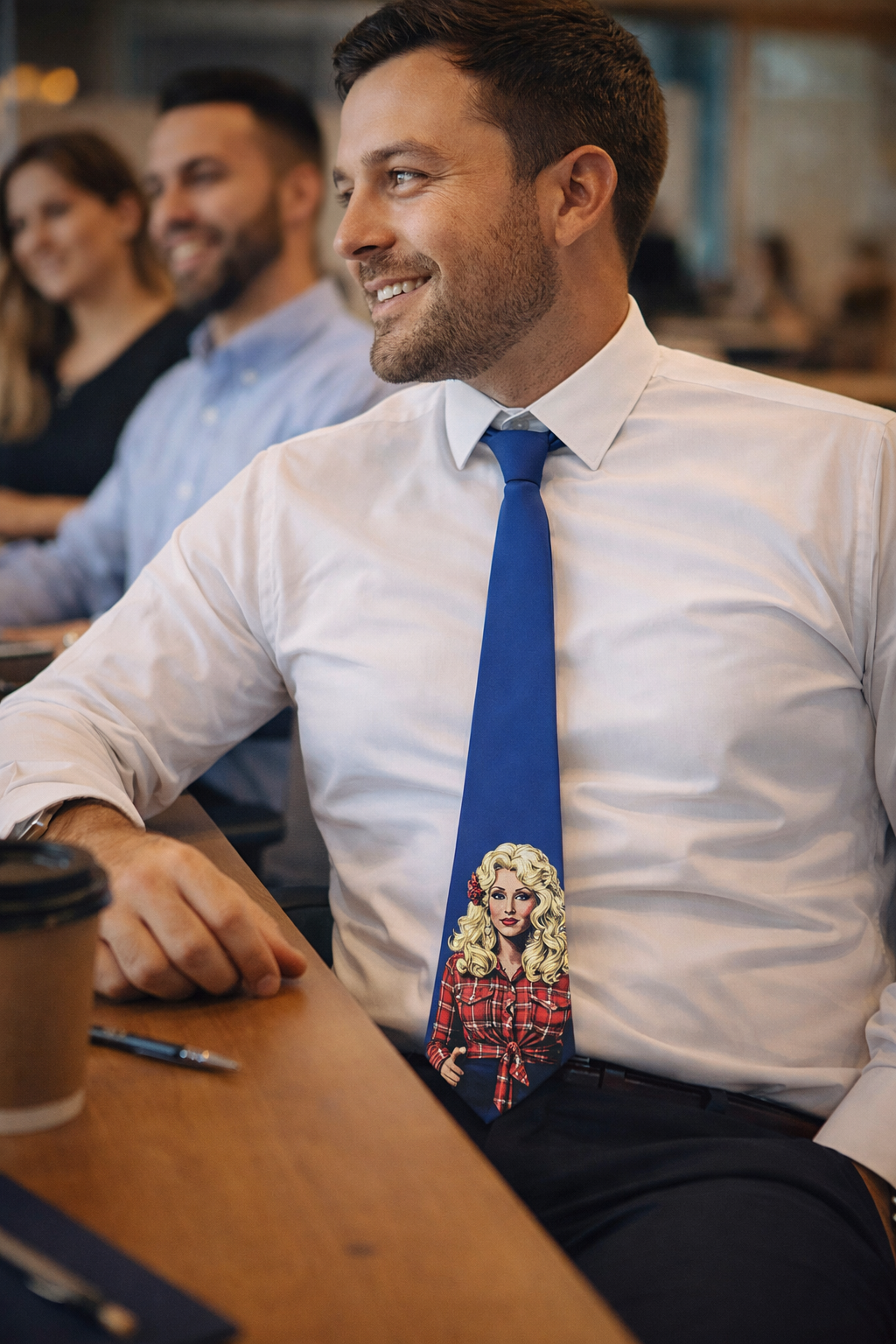 Man wearing a blue Dolly Parton-inspired graphic tie with a white shirt in a casual workplace setting