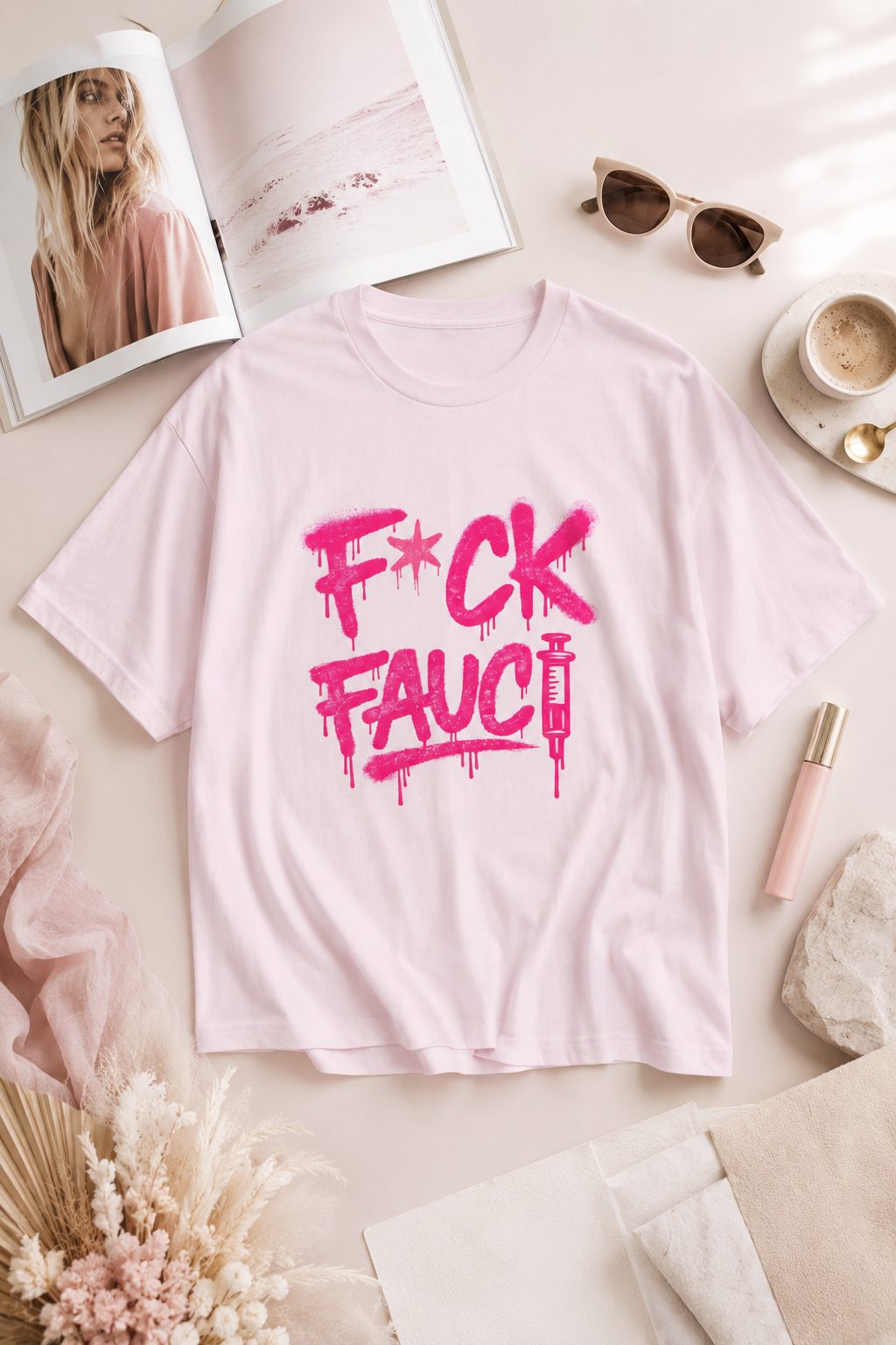 Light pink F*CK Fauci graphic T-shirt styled in a soft editorial lifestyle flat lay