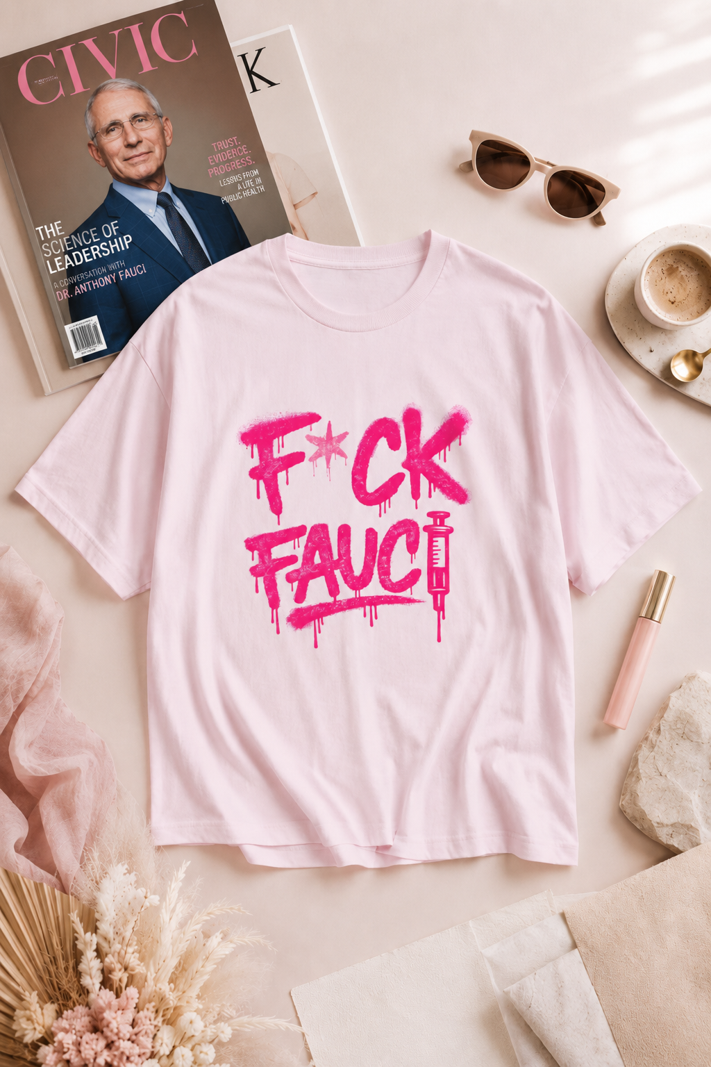 Light pink F*CK Fauci political T-shirt in an editorial flat lay with a Fauci magazine cover