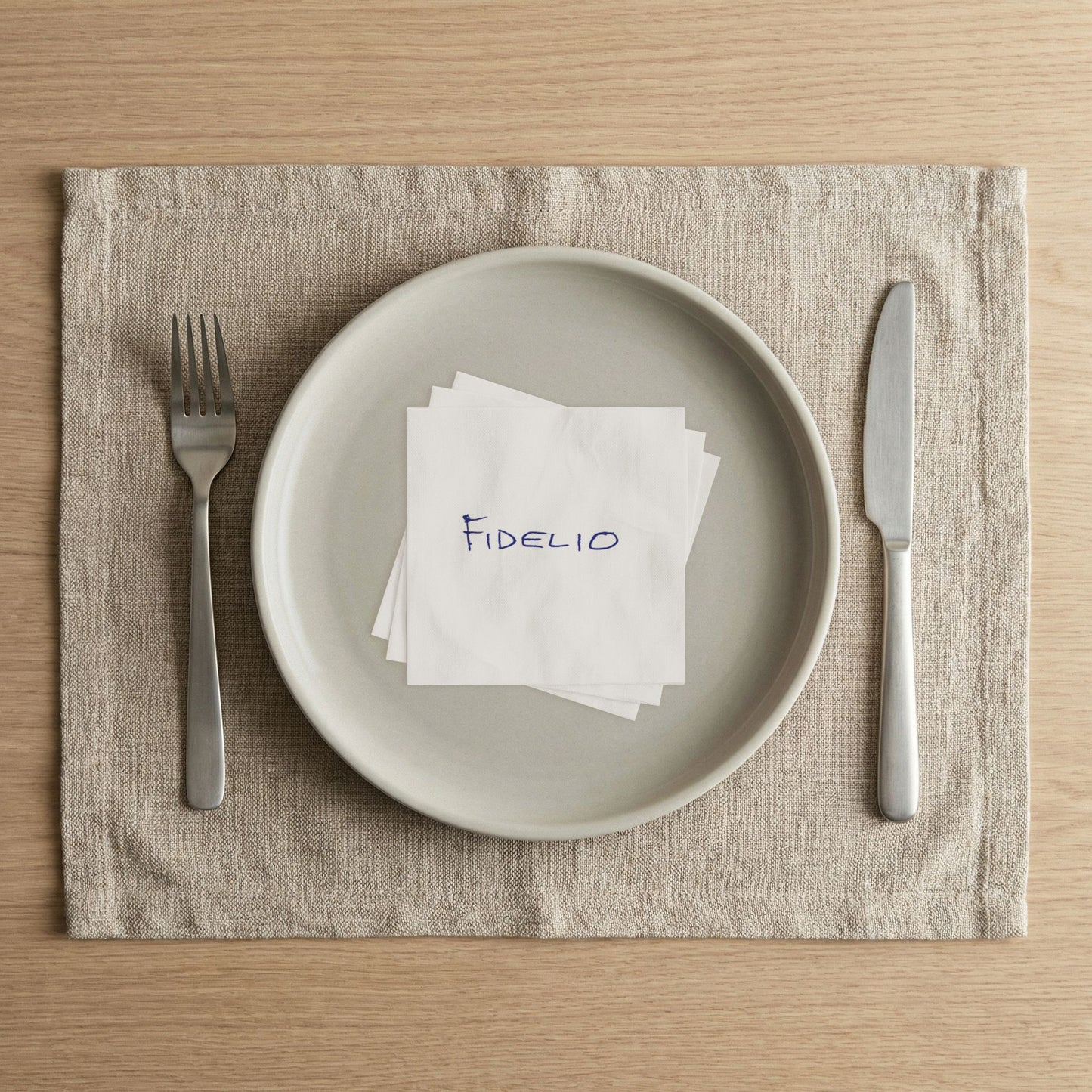 Fidelio Eyes Wide Shut beverage napkin arranged on a white plate in a modern place setting