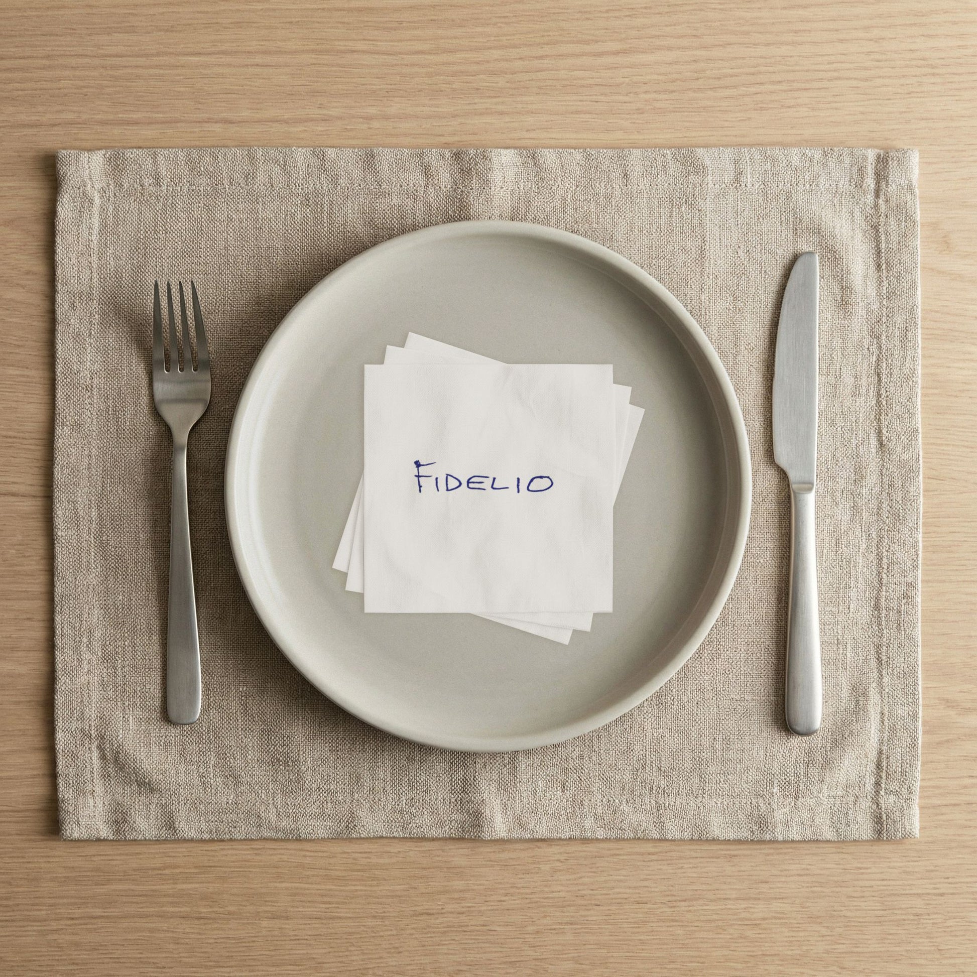 Fidelio Eyes Wide Shut beverage napkin arranged on a white plate in a modern place setting