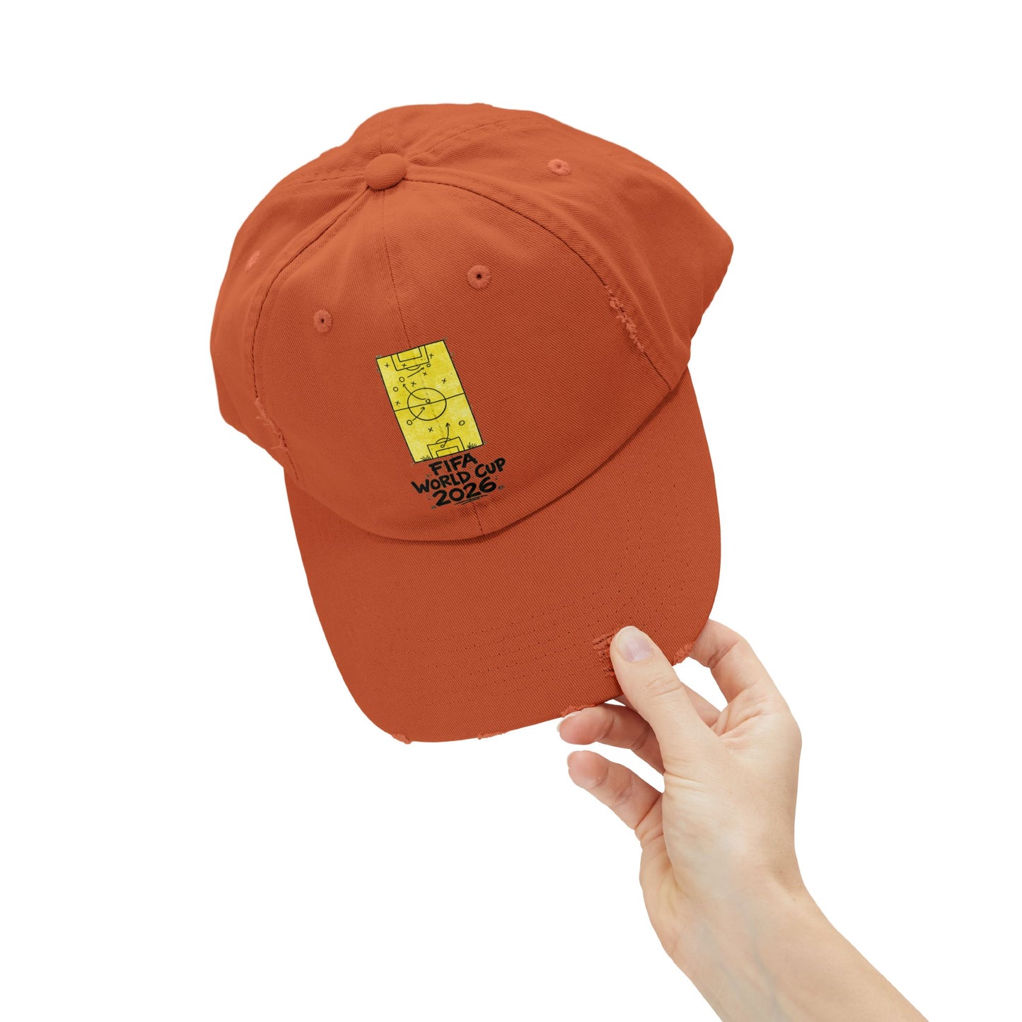 Hand holding burnt orange FIFA World Cup 2026 distressed dad hat close-up product photography