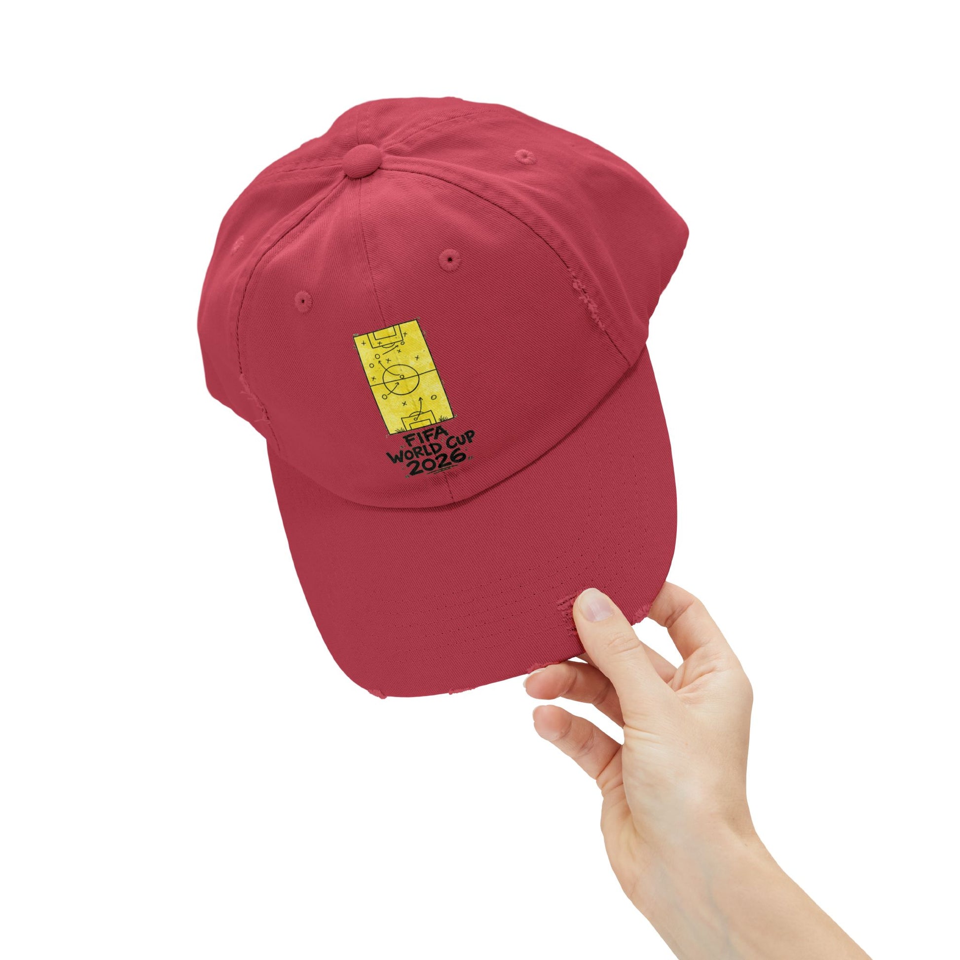 Hand holding red FIFA World Cup 2026 distressed dad hat with football tactics artwork close-up