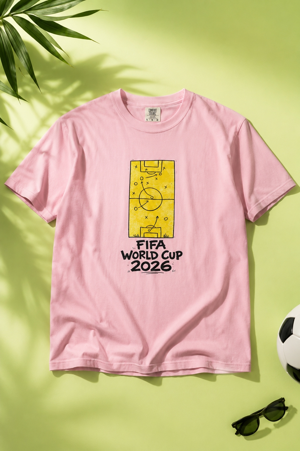 FIFA World Cup 2026 Fan Tee flat-lay photography featuring soccer tactics graphic on a soft lime green gradient background with soccer-inspired lifestyle props