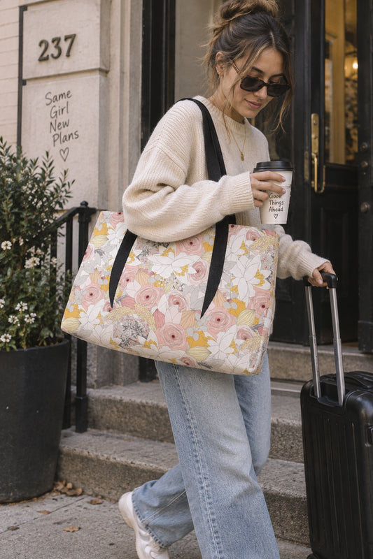 Floral weekender bag carried by traveler with rolling luggage