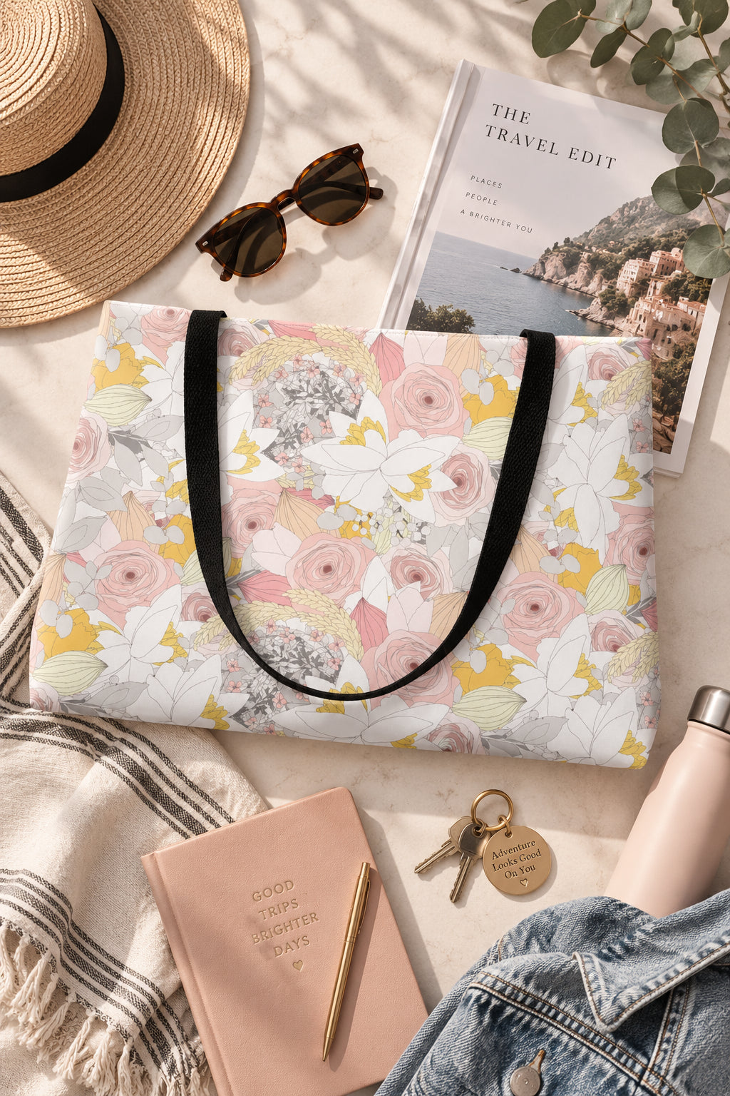Floral weekender travel bag flat lay with sunglasses hat and travel accessories