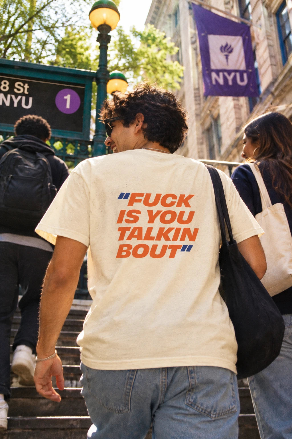Cream Fuck Is You Talkin Bout graphic t-shirt with orange and navy back print worn near NYU in New York City