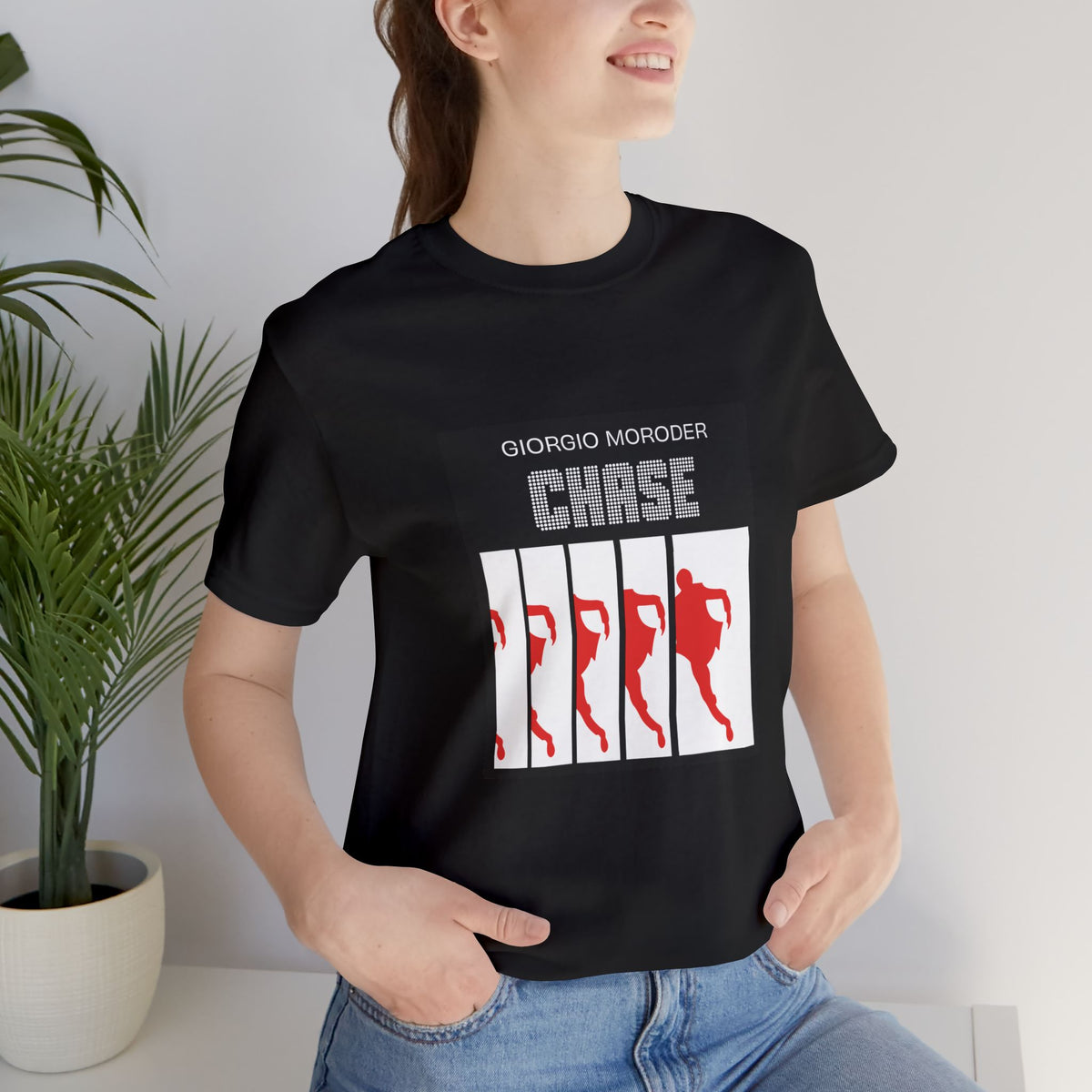 Woman wearing a black Giorgio Moroder Chase T-shirt with the red running figure single-cover graphic.