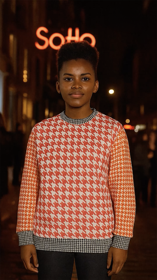Woman wearing the Goose Foot Pattern Sweatshirt in pink, orange, black and white on a Soho street at night.