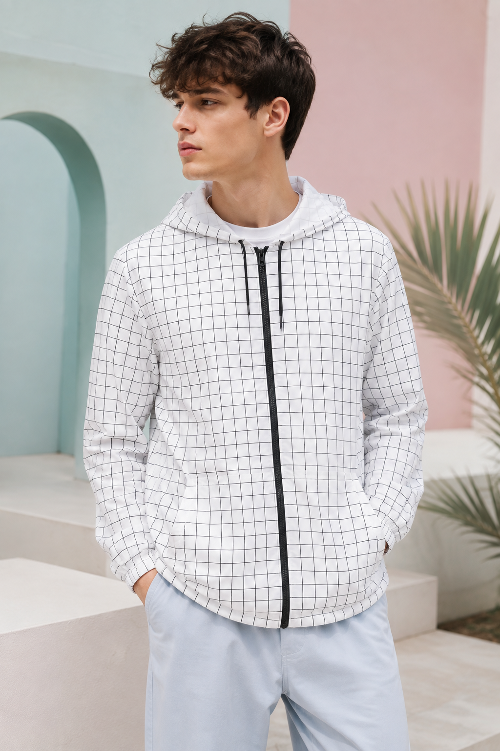 Man wearing a lightweight black and white grid windbreaker jacket in a pastel setting