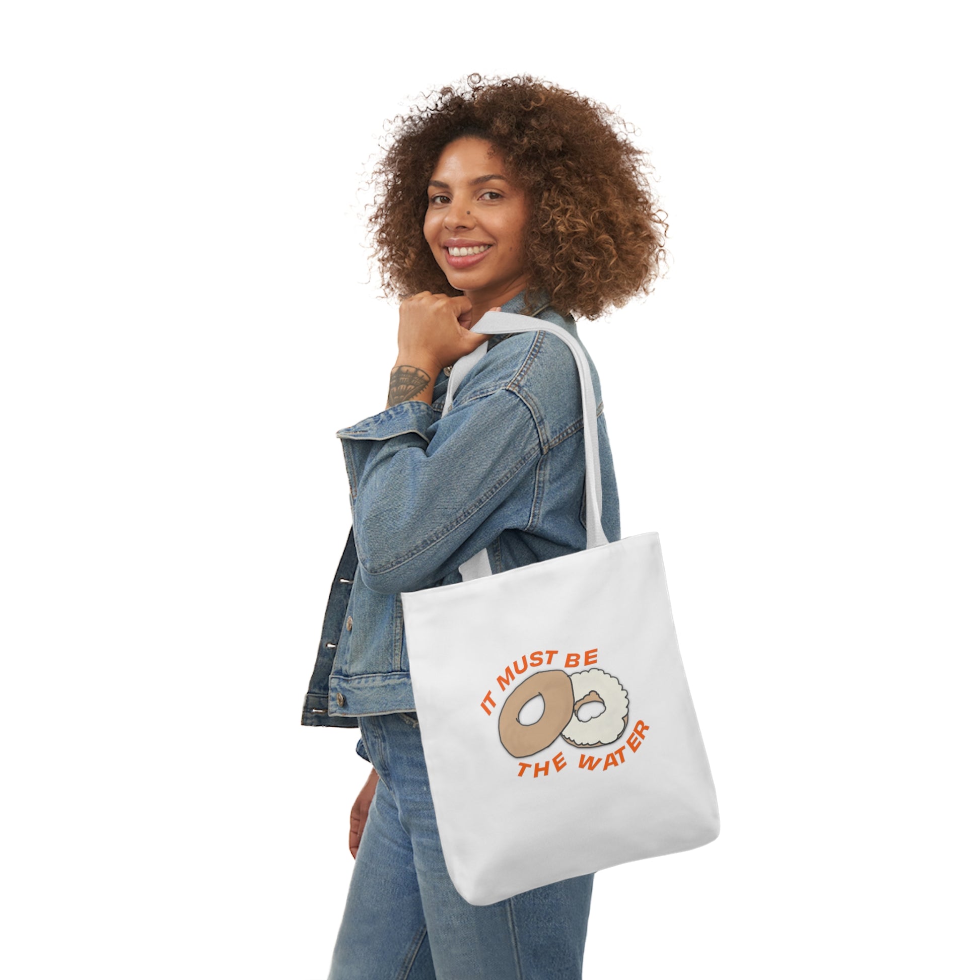 Woman carrying a hand-drawn NYC bagel tote bag from the Tantrum Media New Yorker Collection.