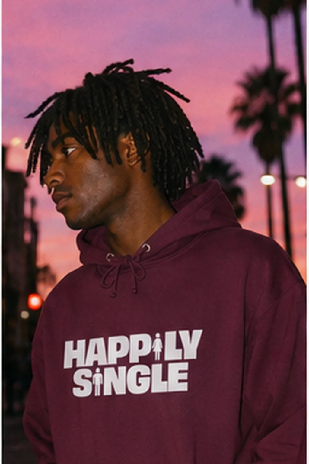 Gen Z man wearing burgundy Happily Single hoodie against dramatic sunset sky