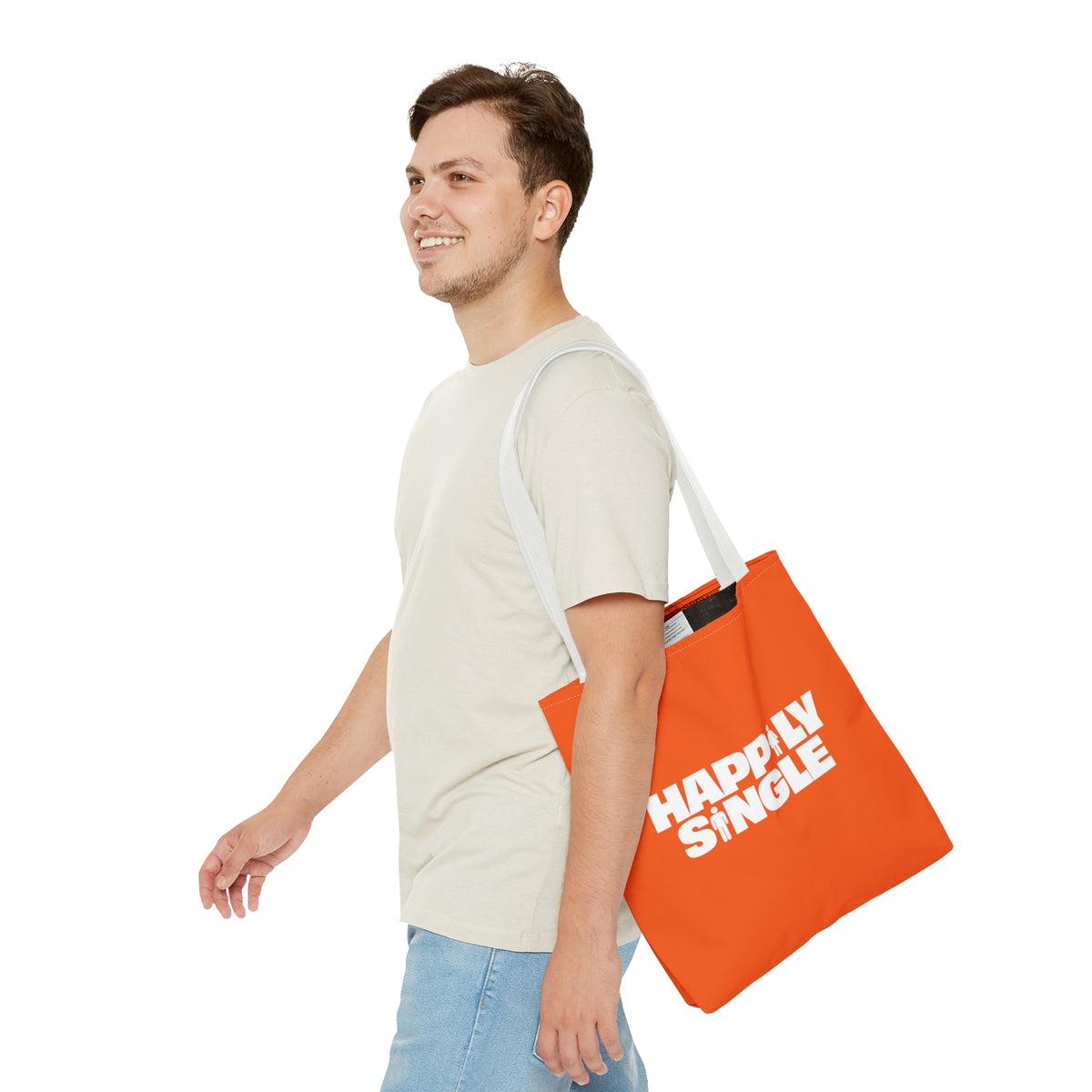 Young man carrying an orange Happily Single tote bag in a clean casual lifestyle product mockup.