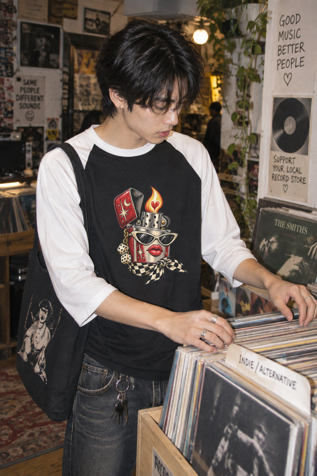 Young man wearing the black and white Heartstarter graphic baseball tee while browsing vinyl records in an independent record store.