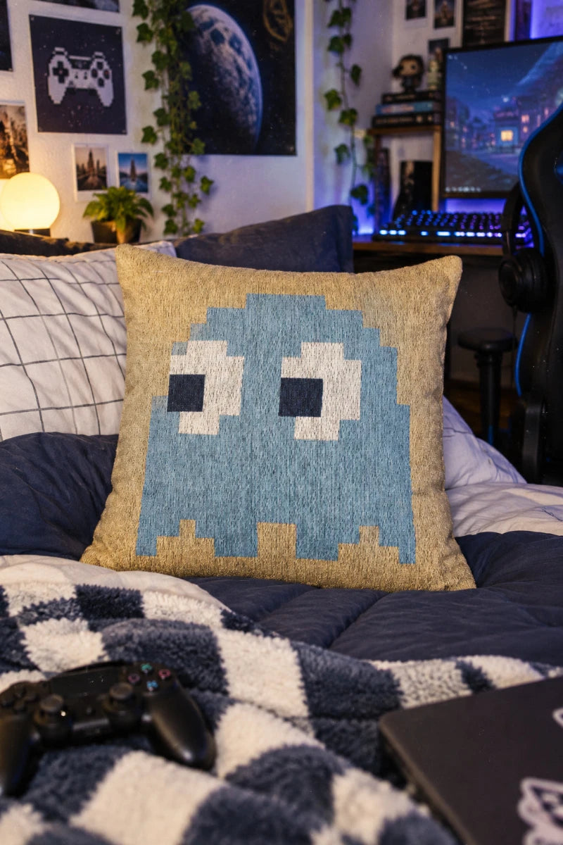 Inky Pac-Man ghost woven throw pillow styled in a college gamer bedroom with retro gaming decor