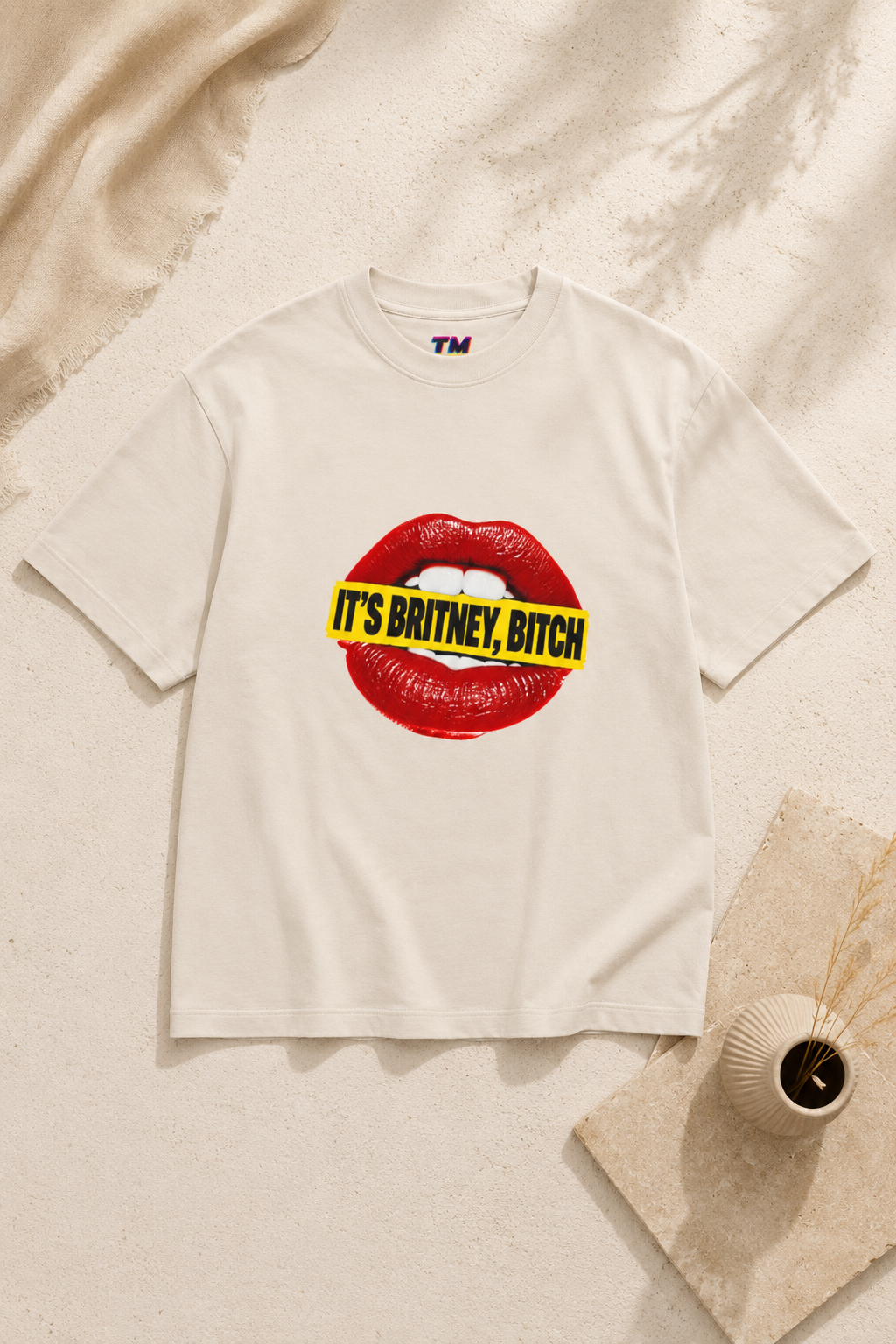 Front view of the cream It’s Britney, Bitch graphic T-shirt with red lips and yellow statement artwork.