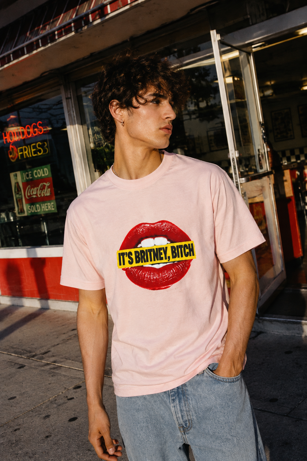 Gen Z woman wearing the pink It’s Britney, Bitch graphic T-shirt in a stylish café scene.