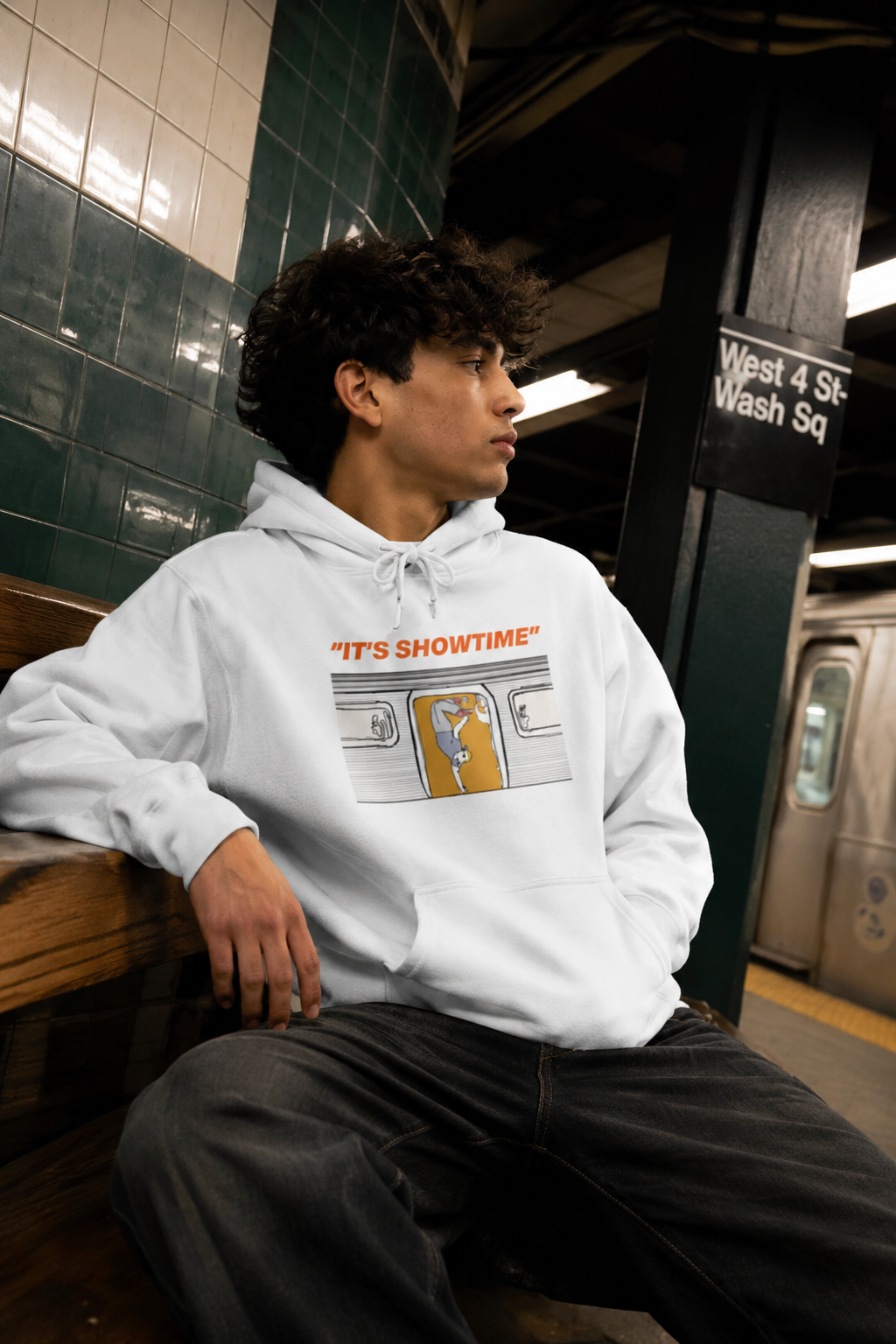 Gen Z man wearing the white It’s Showtime graphic hoodie at West 4th Street subway station in New York City