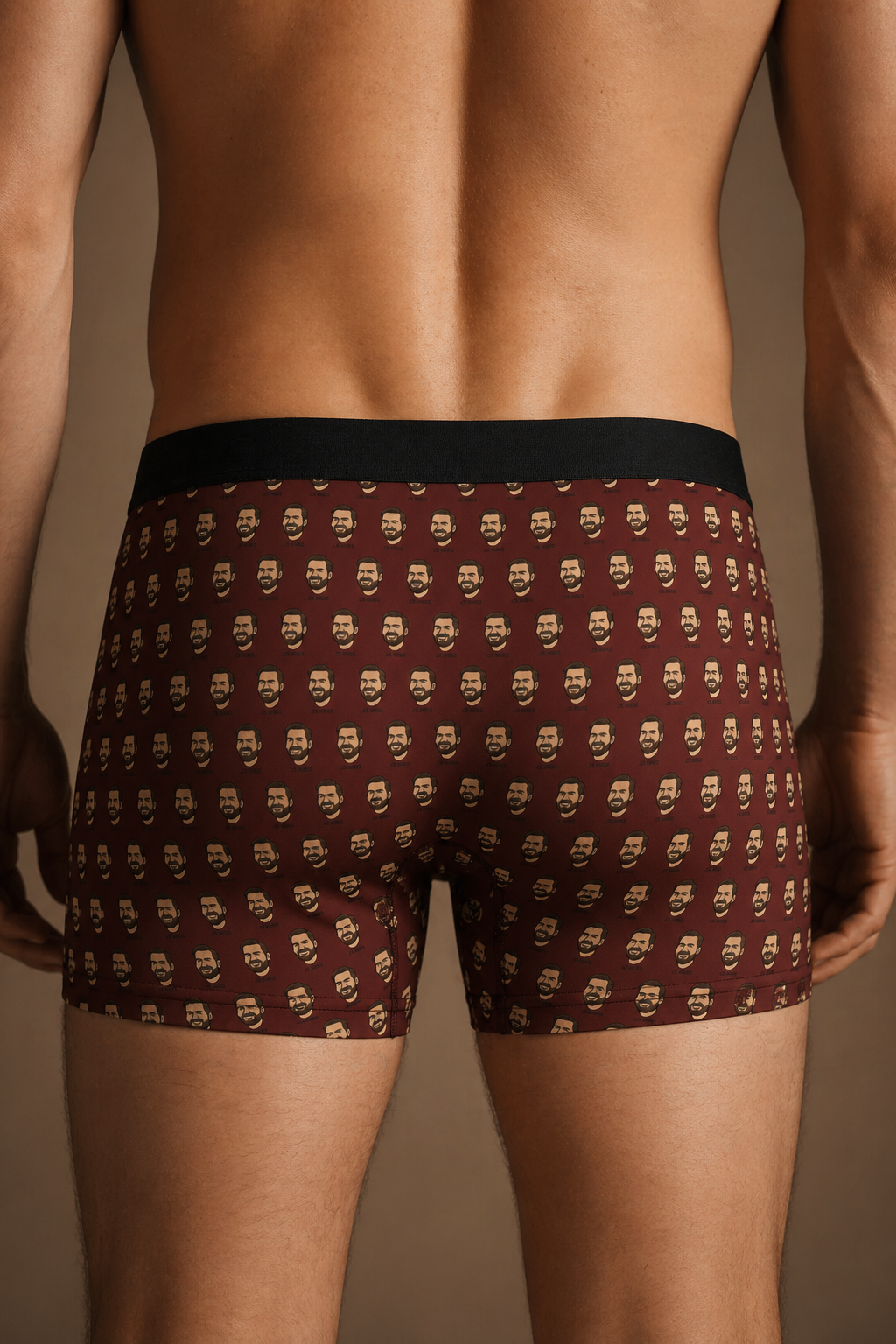 Close-up back view of brown boxer briefs with repeating cartoon face pattern, fitted men’s graphic underwear