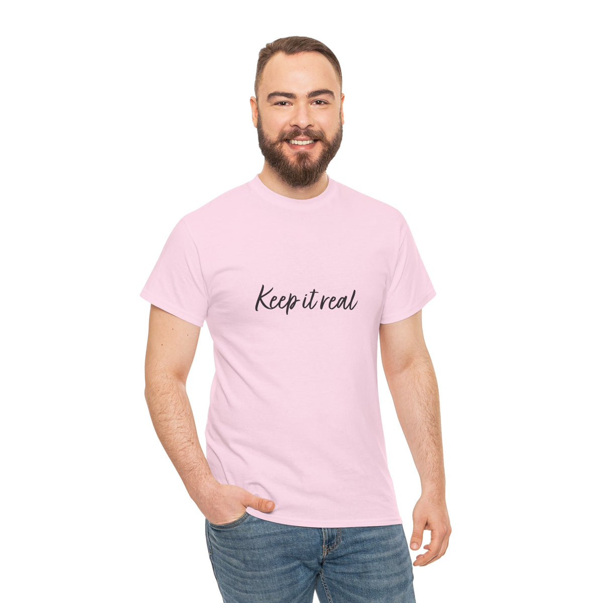 Man modeling Tantrum Media’s light pink Keep It Real T-Shirt with black script lettering and blue jeans.