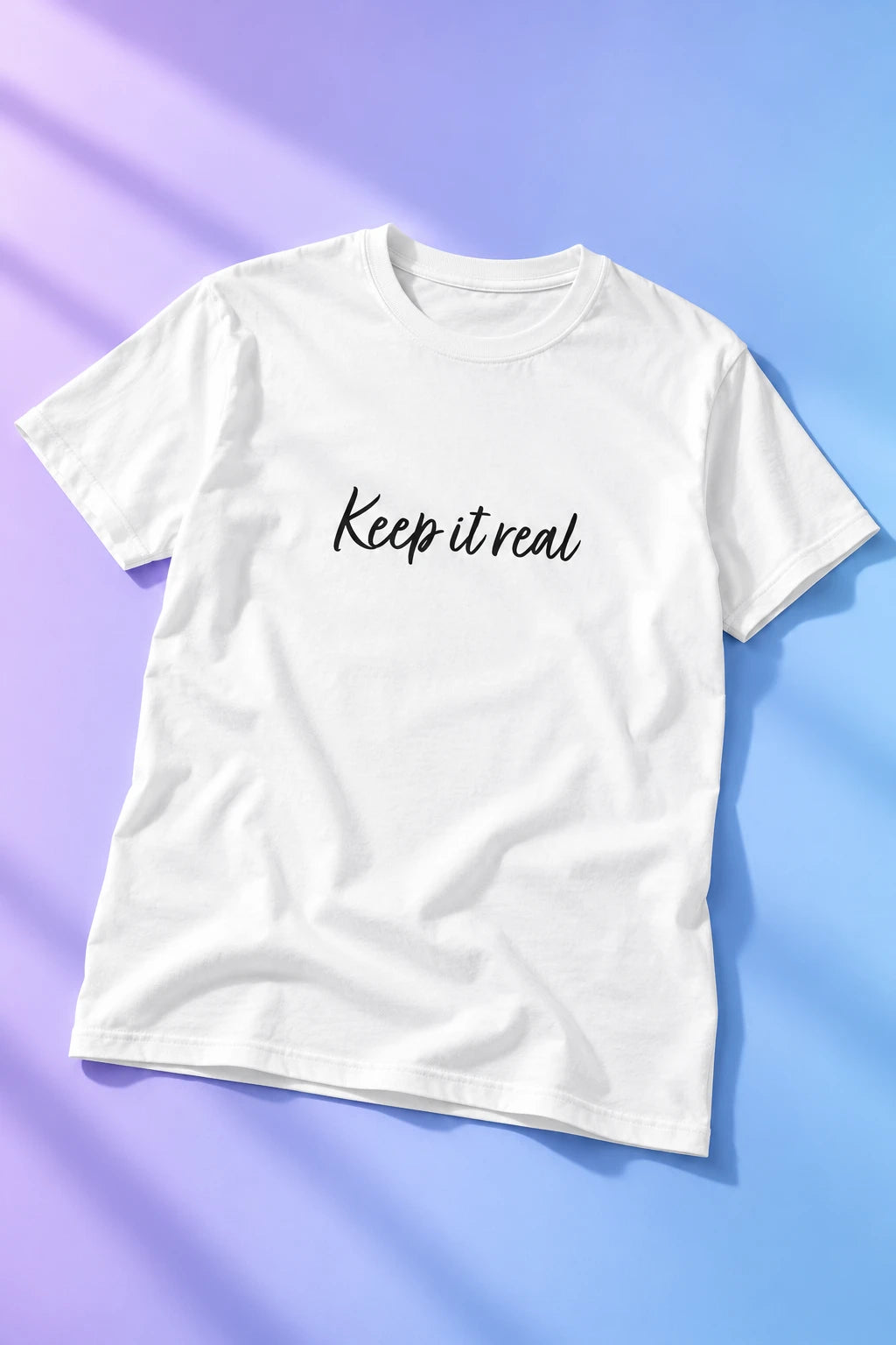 Tantrum Media white Keep It Real T-Shirt with black script lettering on a lavender and blue gradient background.