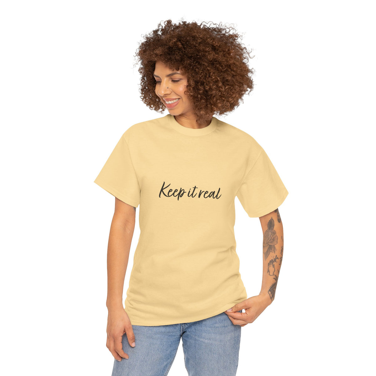 Woman with curly hair modeling Tantrum Media’s yellow Keep It Real T-Shirt with black script lettering and jeans.