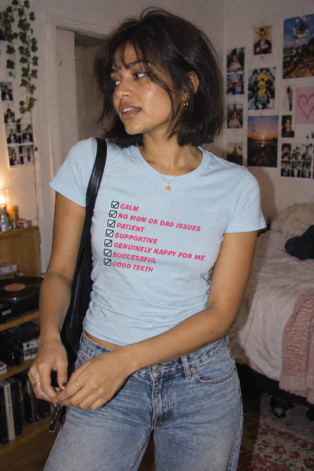 Woman wearing light blue Kim Kardashian Boyfriend Must Have List women’s T-shirt with pink checklist graphic