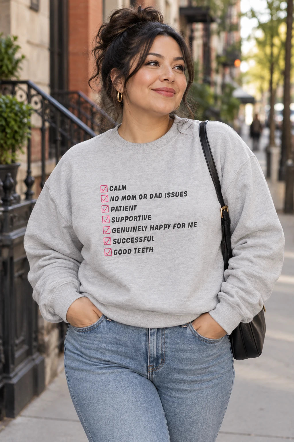 Gray Kim Kardashian’s Men’s Must-Have List crewneck sweatshirt on a woman walking outdoors in a city street scene.