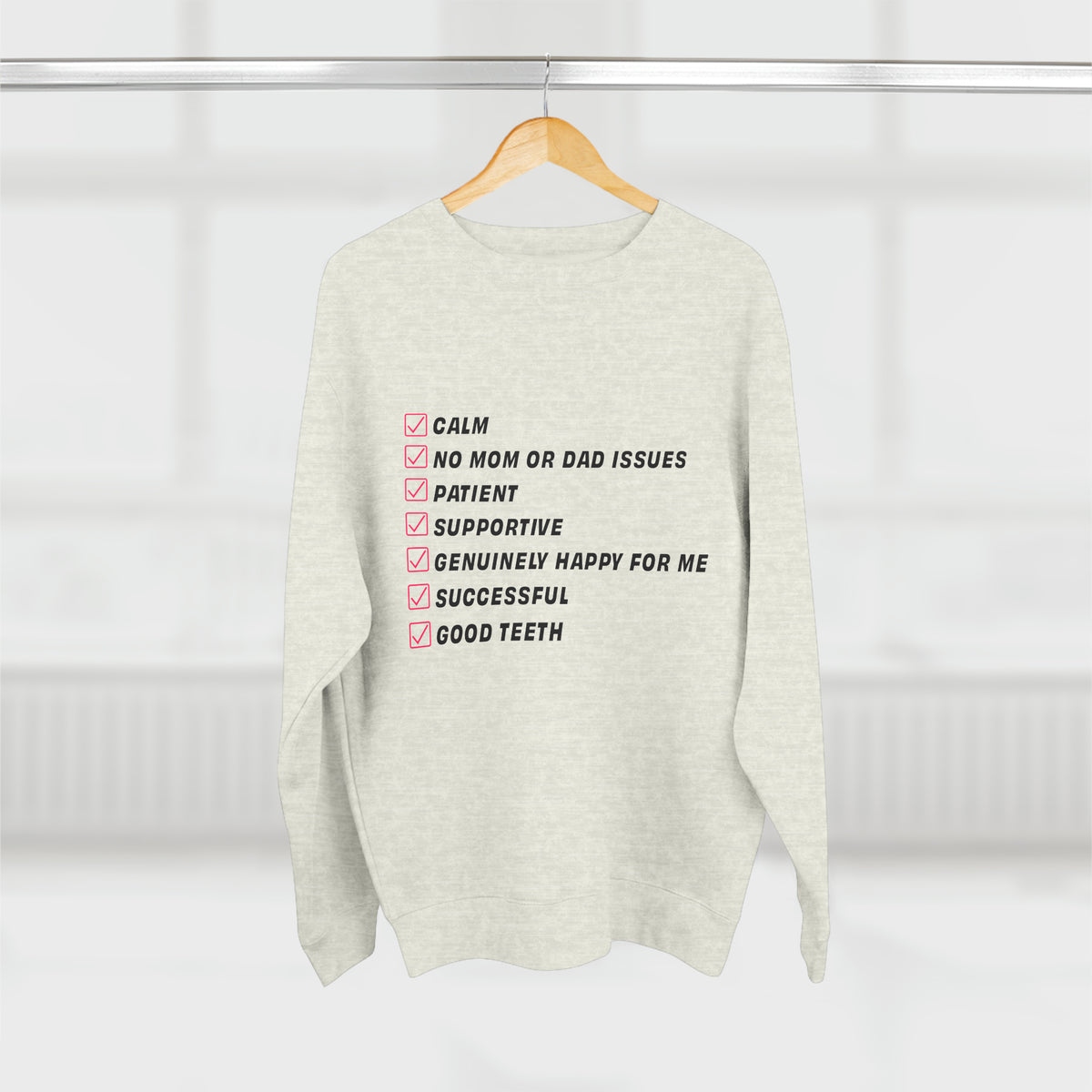 Oatmeal Kim Kardashian’s Men’s Must-Have List crewneck sweatshirt hanging front view with checklist graphic.
