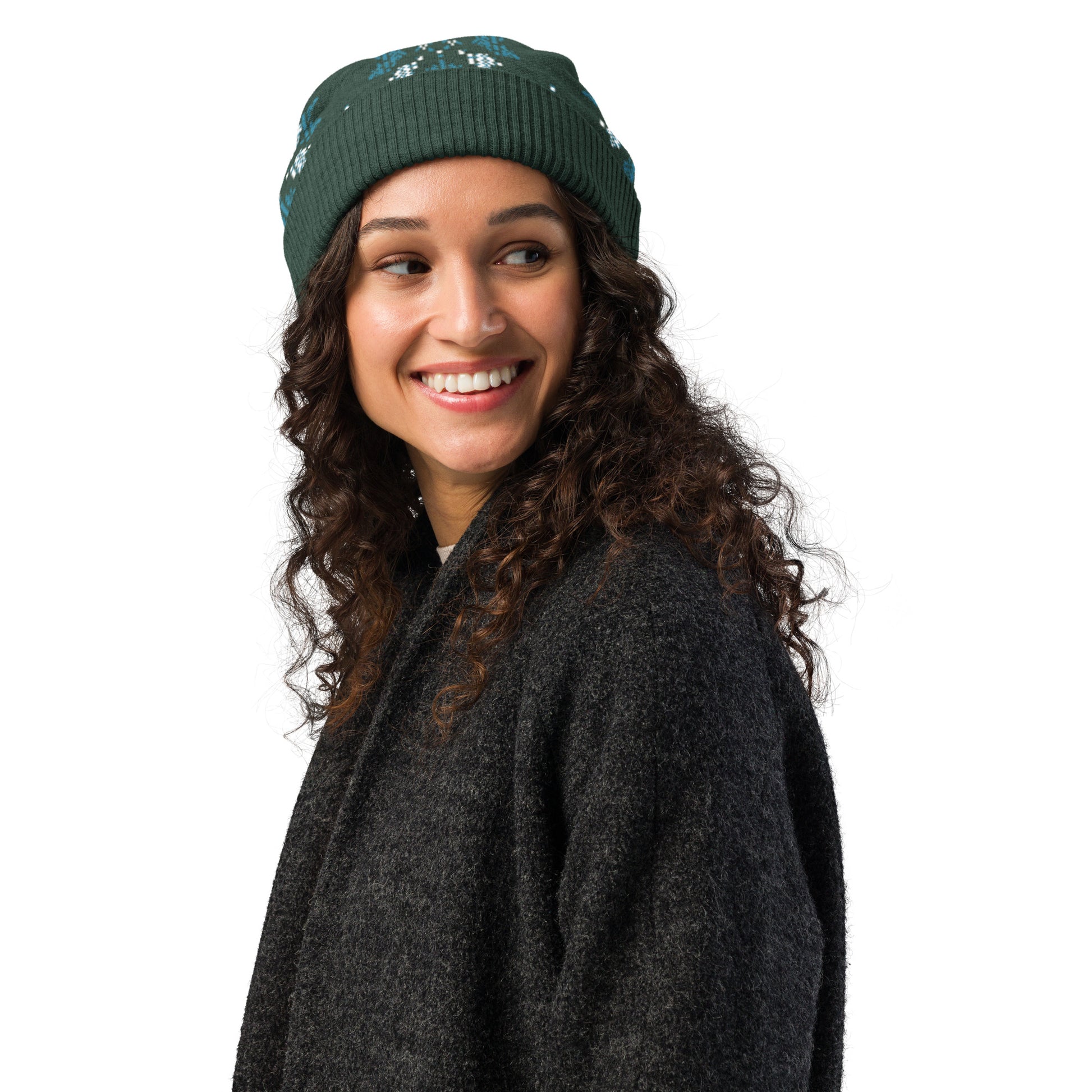 Smiling person wearing the dark green winter patterned beanie and a dark sweater in studio lighting.
