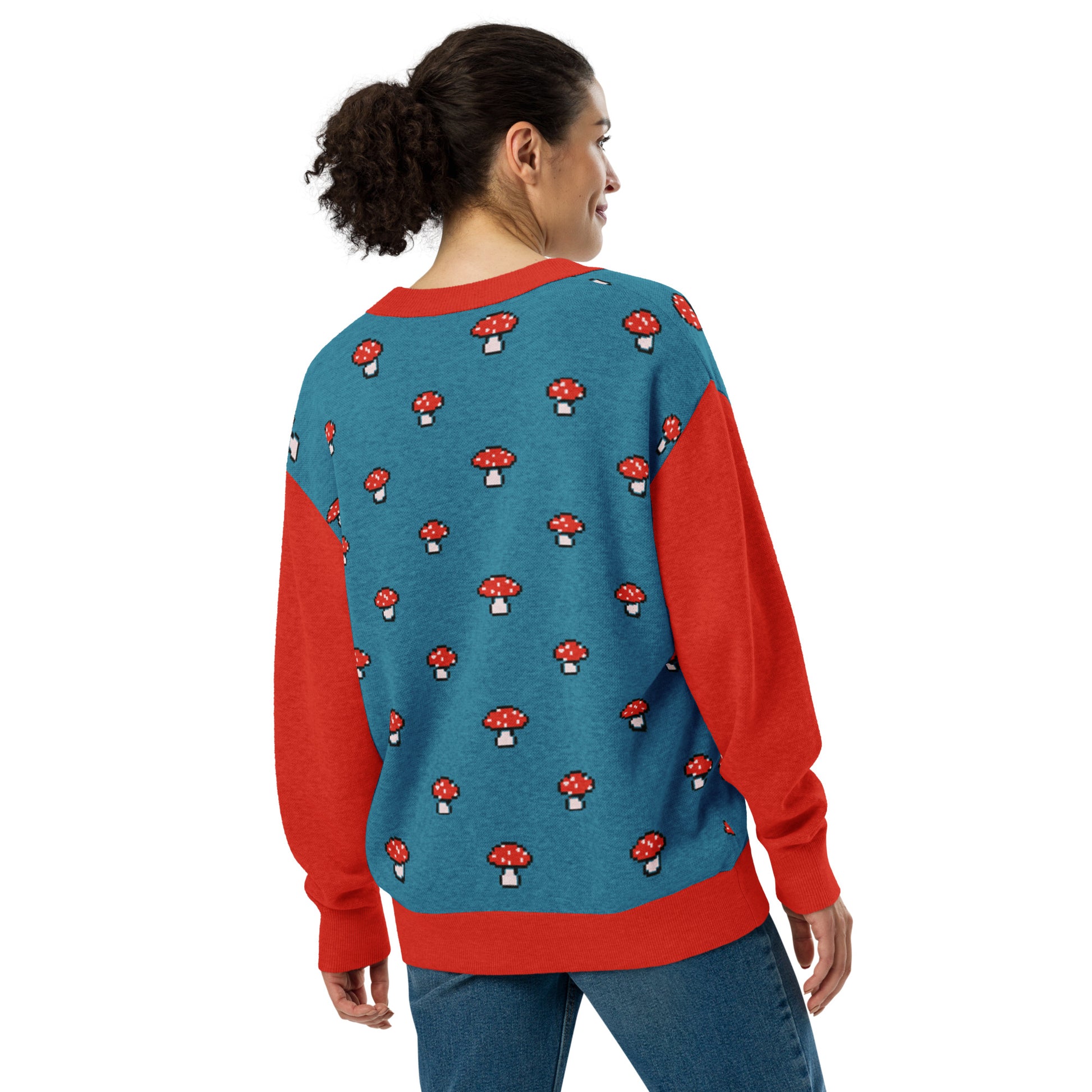 Woman wearing the pixel mushroom cardigan in a studio pose with hands in pockets.