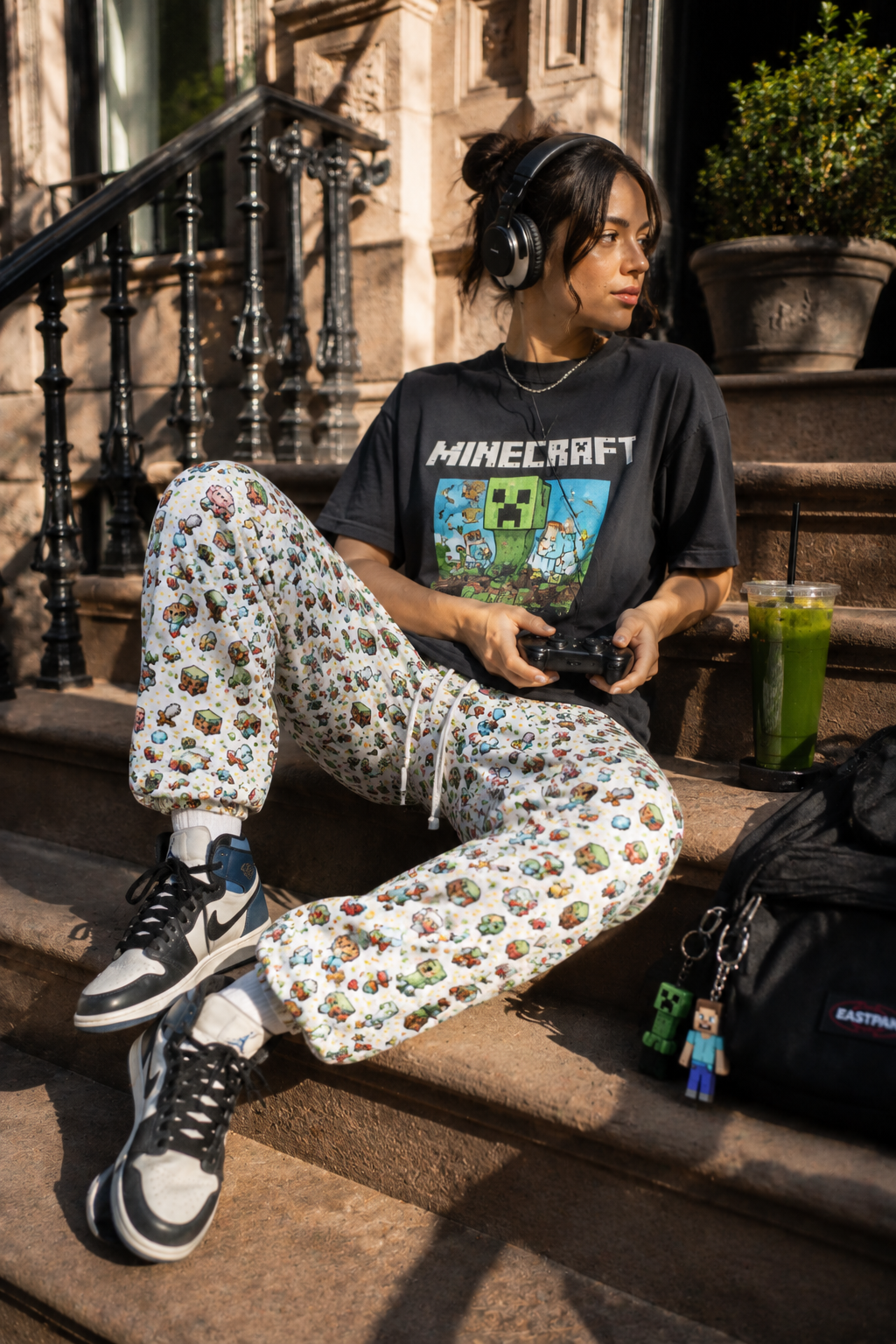 Model wearing Level Up Gamer Joggers with pixel gaming print while sitting outdoors in streetwear styling.