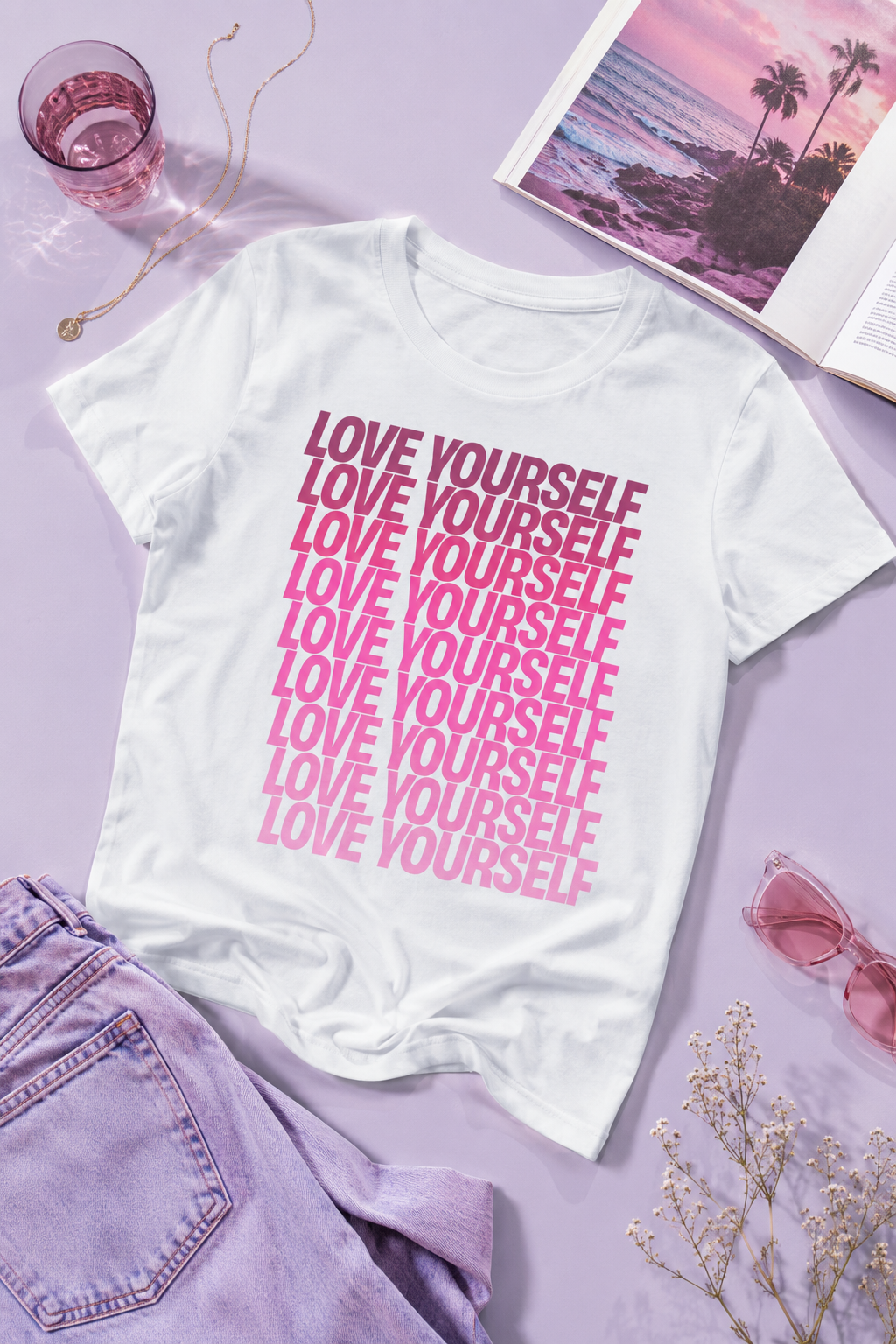 Love Yourself graphic unisex T-shirt in white displayed in a flat lay with pink aesthetic accessories.