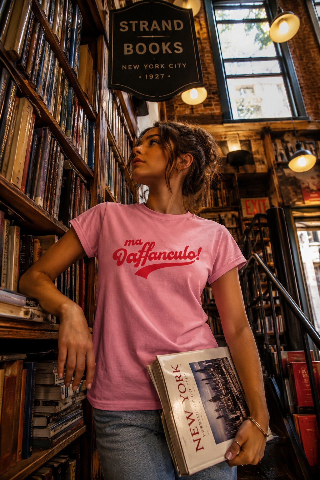 Woman wearing the pink Ma Vaffanculo graphic t-shirt inside a vintage NYC bookstore.