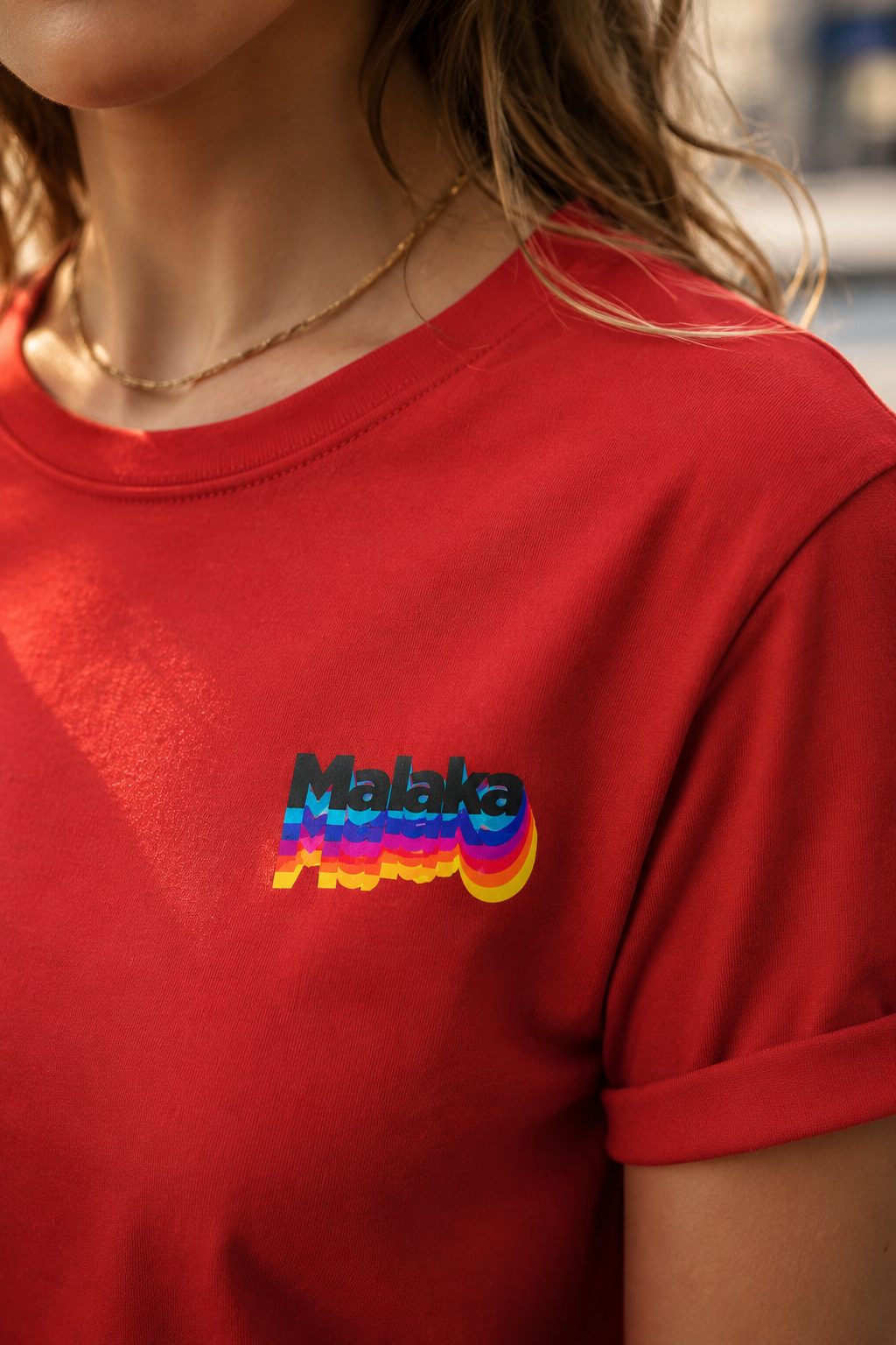 Woman wearing a red Malaka Greek slang T-shirt with a colorful left chest graphic, close-up detail