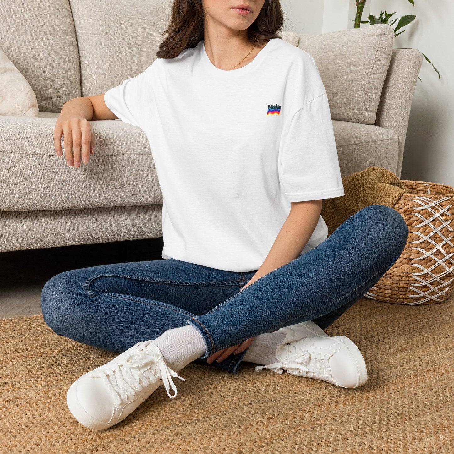 Woman wearing a white Malaka Greek slang T-shirt while seated indoors in a casual lifestyle setting