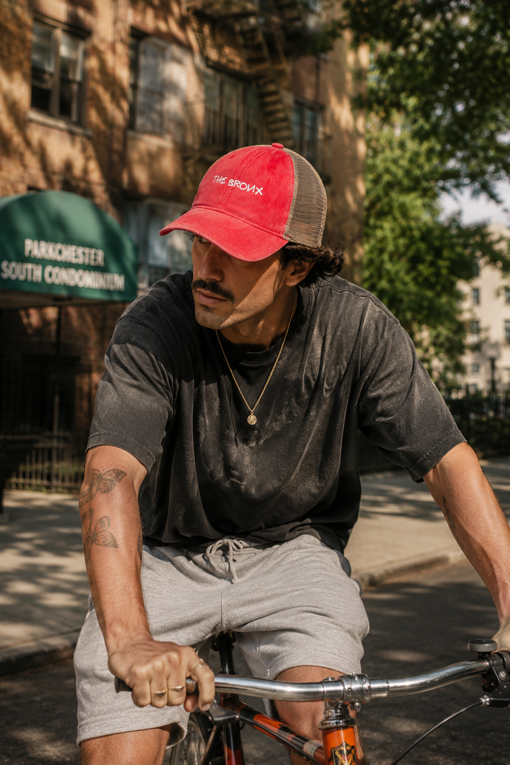 Man wearing The Bronx vintage red trucker hat while riding a bicycle.