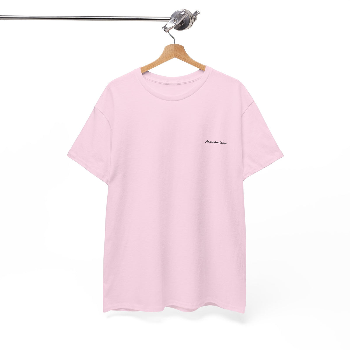 Pink Manhattan T-shirt on a wooden hanger, showing its short sleeves and small black script chest print.