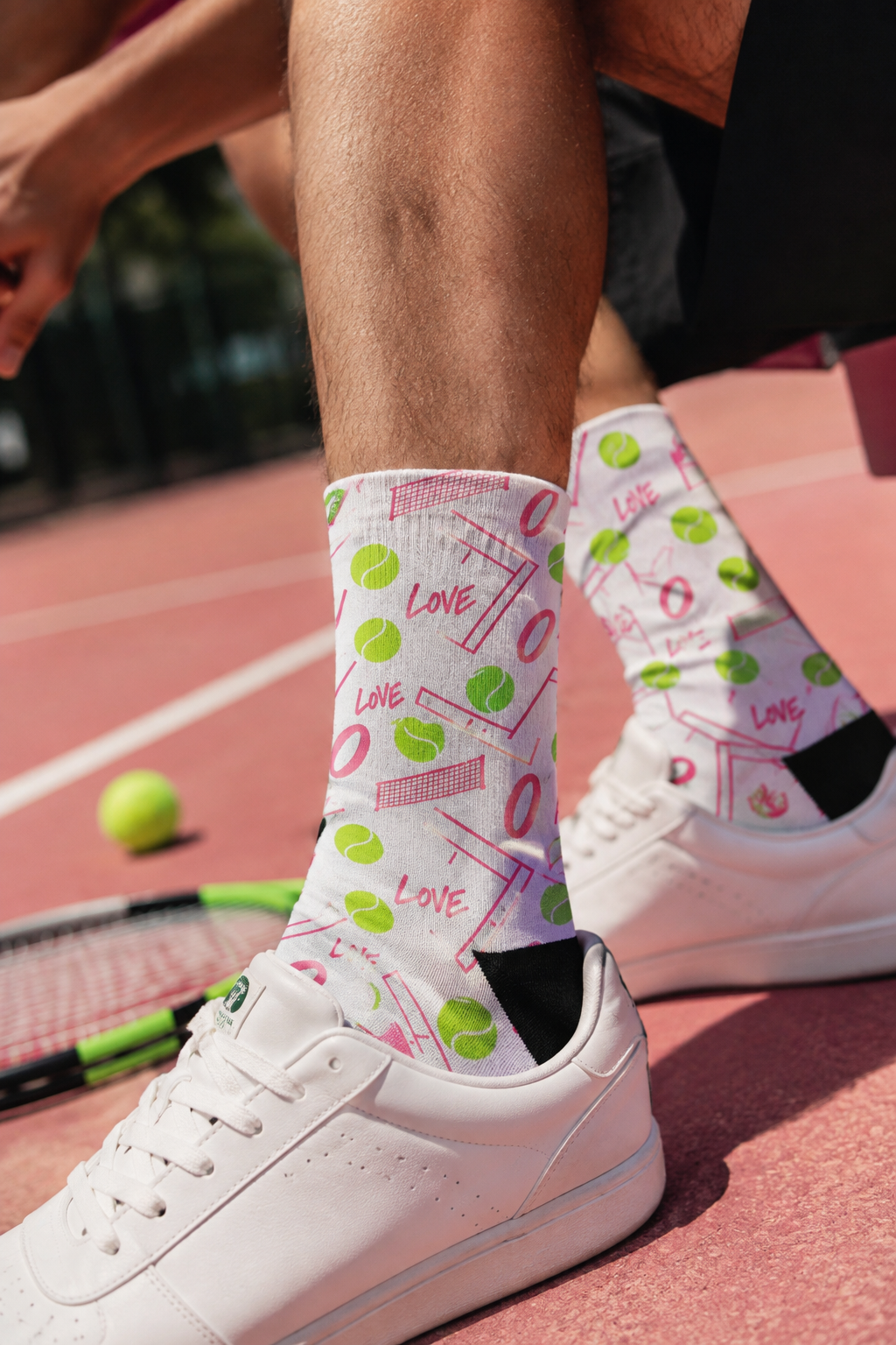 Male model wearing Love Zero tennis crew socks on a pink tennis court