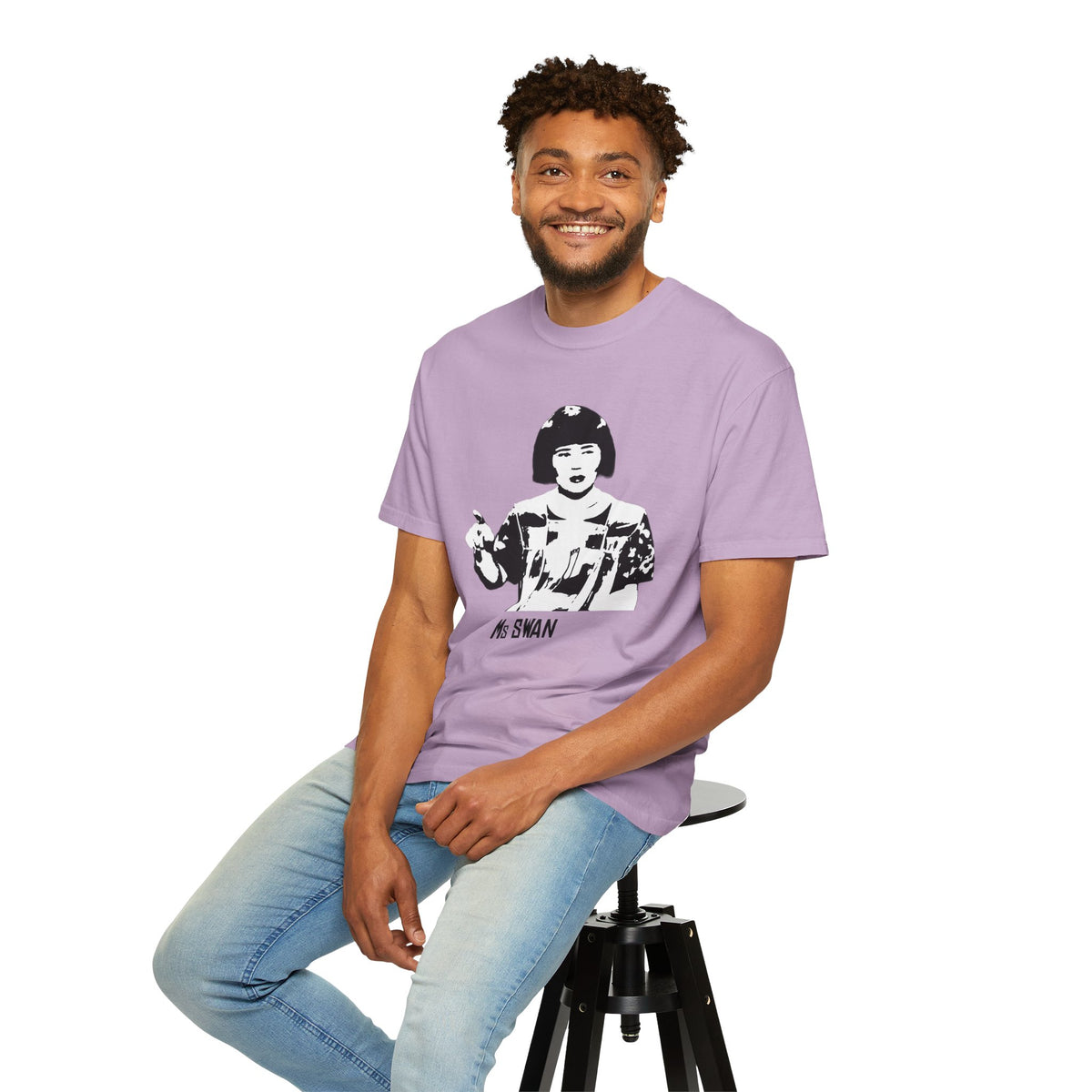 Seated model wearing the Tantrum Media Ms Swan T-Shirt in lavender with light blue jeans against a white studio background.
