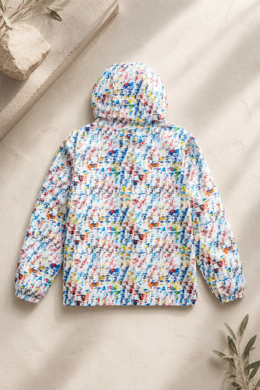 Back view of multicolor abstract print unisex windbreaker jacket in an editorial flat lay